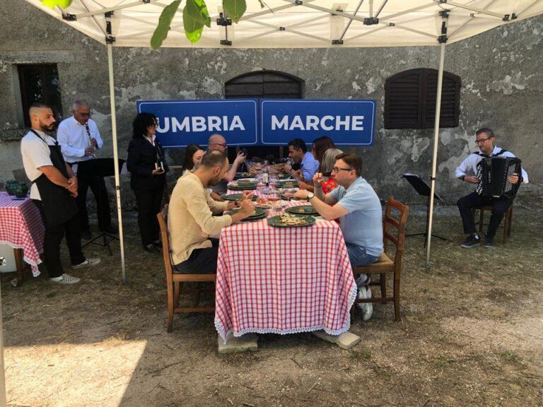 Inedito pranzo di ferragosto, tra Umbria e Marche. Il tavolo collocato esattamente nella linea che divide i due comuni, a Pian della Serra 