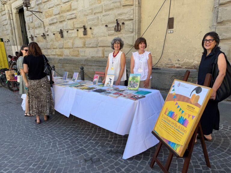 Biblioteca in “piazza”: postazione piena di libri fra le bancarelle del mercato nel centro storico